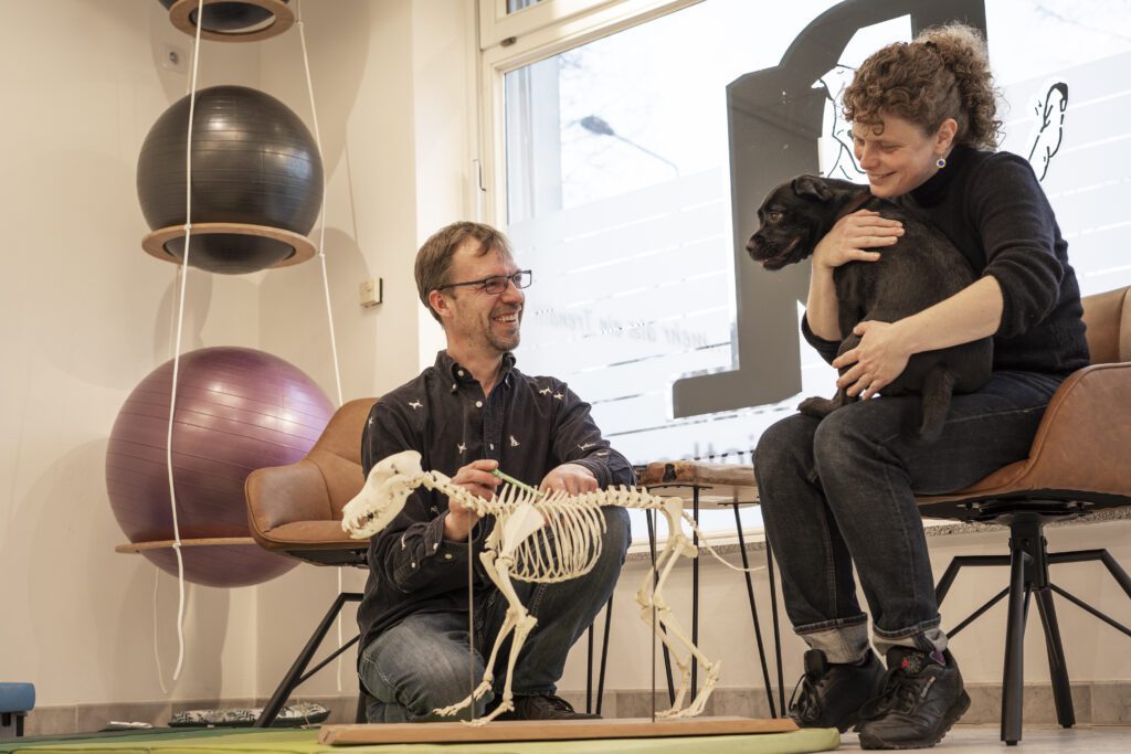 Dieter Lützel erklärt Halterin die Anatomie des Hundes anhand eines Skeletts